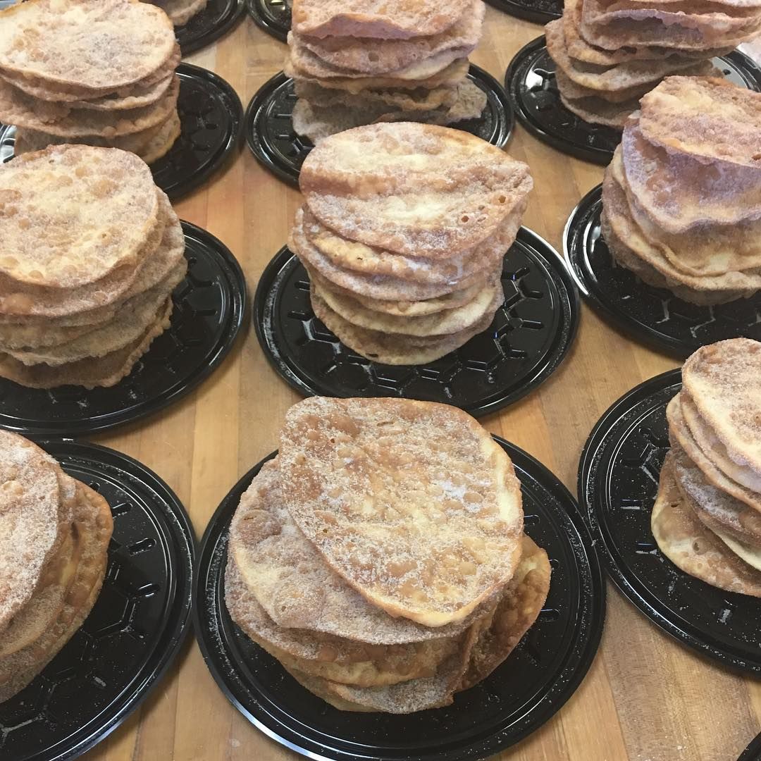 Stacks of sugared bunuelos on trays at La Popular Panaderia