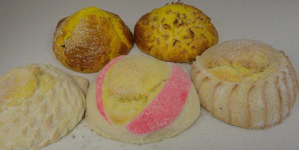 Assorted pan dulce including a pink striped concha at La Popular Panaderia