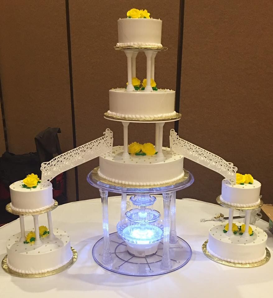 Tall white fountain wedding cake with yellow roses made by La Popular Panaderia